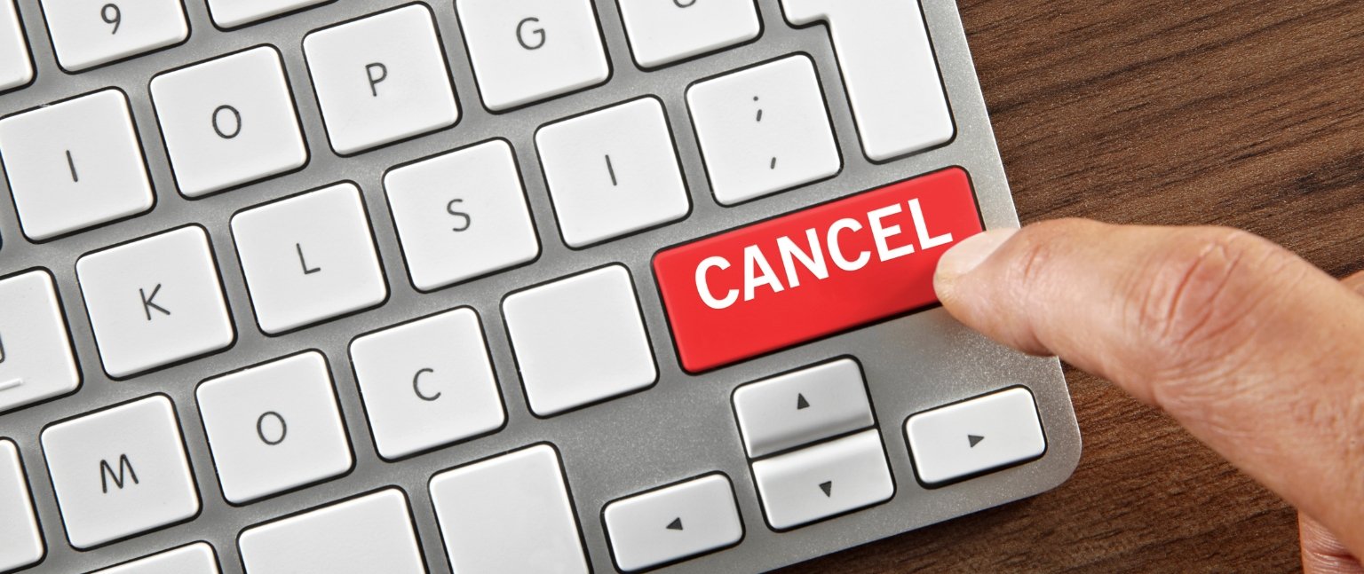 Χέρι πατά κόκκινο πλήκτρο «Cancel» σε πληκτρολόγιο, συμβολίζοντας ακύρωση παραγγελίας.